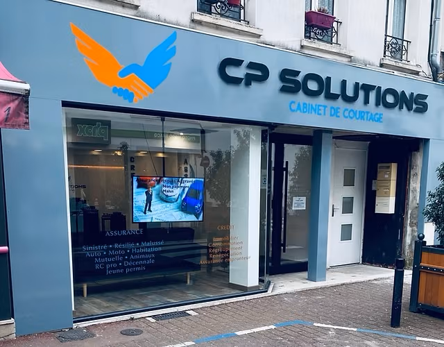 La devanture de CP SOLUTIONS au 35 rue Jean Jaurès à Montereau-Fault-Yonne : enseigne bleue au logo de deux mains qui se serrent, vitrine listant les assurances et les crédits proposés, porte d'entrée vitrée.
